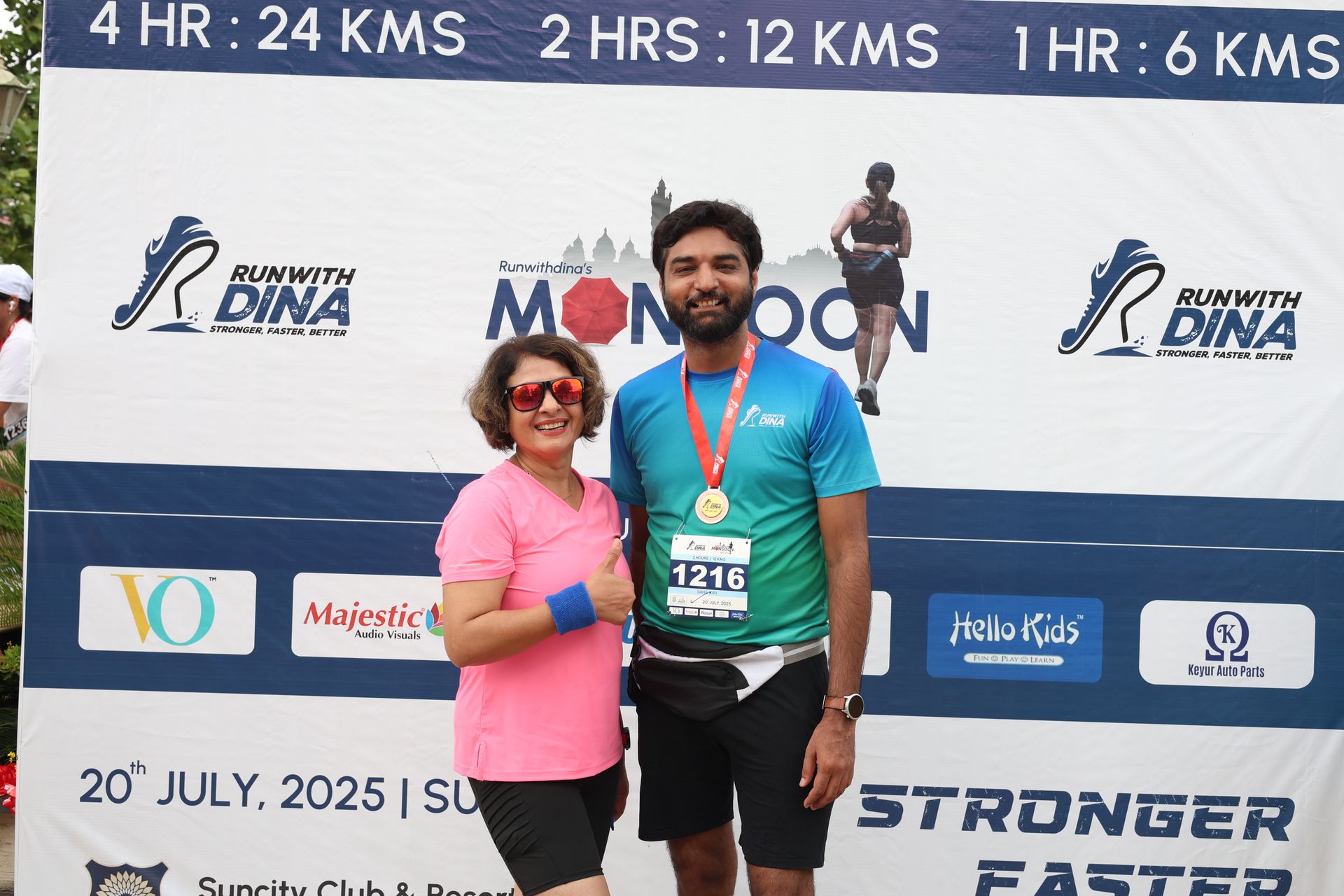Couple posing with medal at backdrop